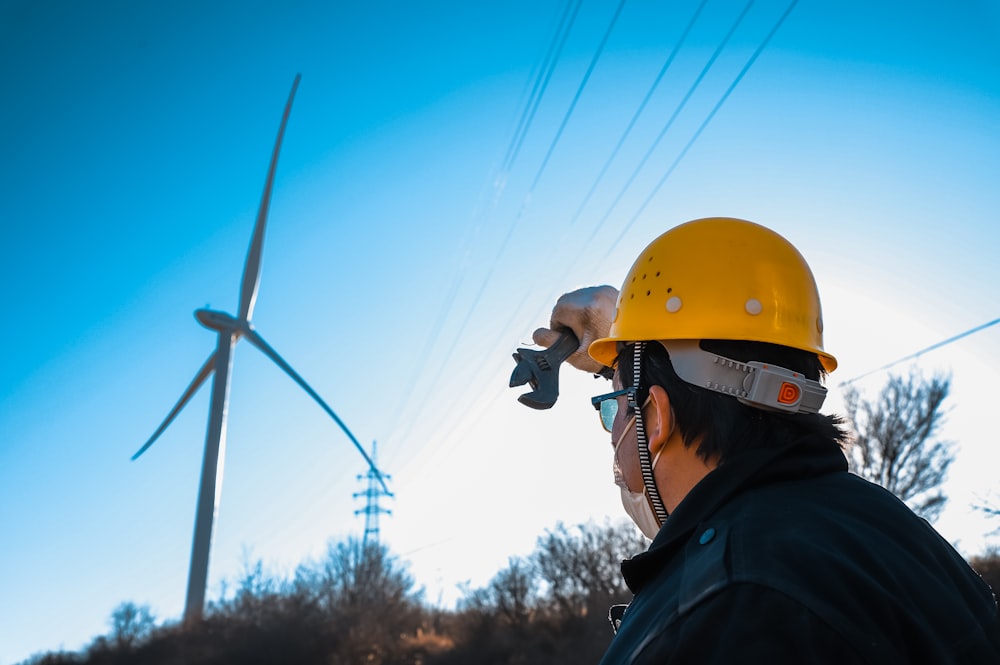 Técnico con casco y chaleco ante un parque eólico