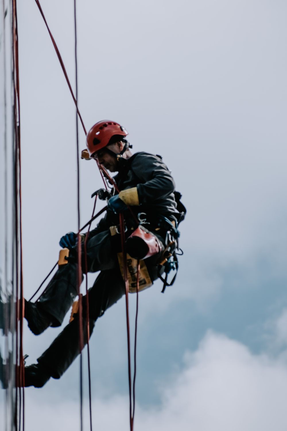 Técnico con EPIs completos suspendido de cuerdas en un aerogenerador